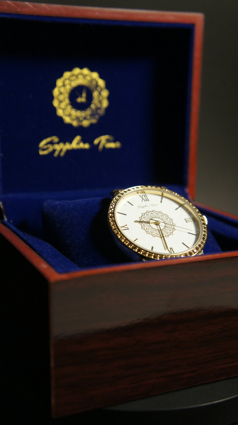 Orologio di lusso posato all'interno di una scatola di presentazione in legno scuro aperta.