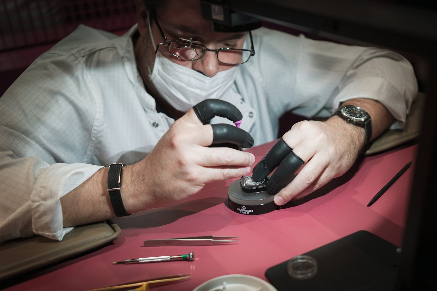 Orologiaio che assembla con cura un movimento di orologio al suo banco di lavoro.