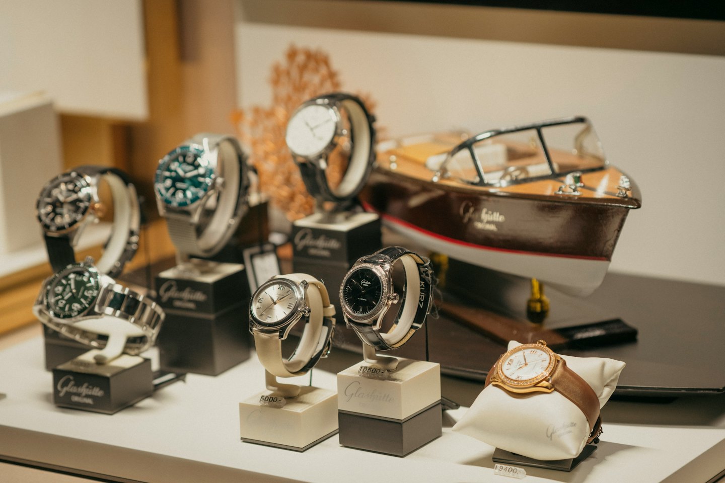 Orologi di lusso esposti su piedistalli con una barca modello.